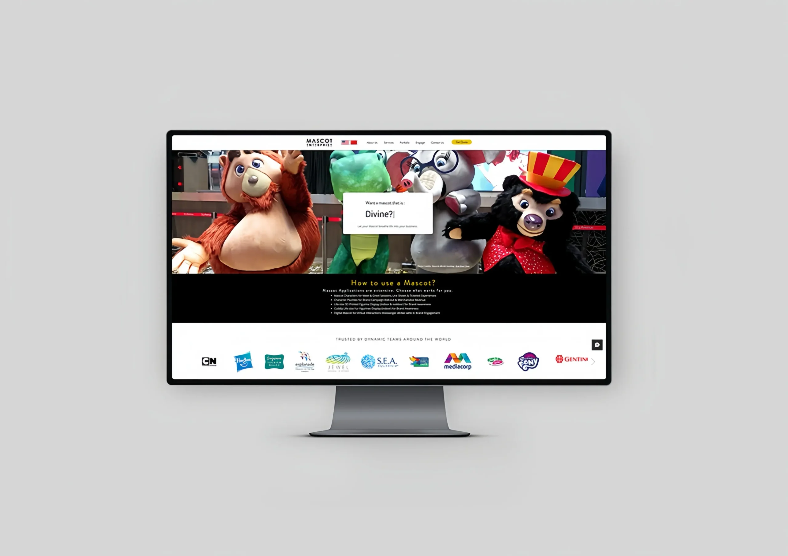 Desktop monitor displaying the original Mascot Enterprise website homepage, featuring photos of various real-life mascot costumes and client logos on a white and dark grey background.
