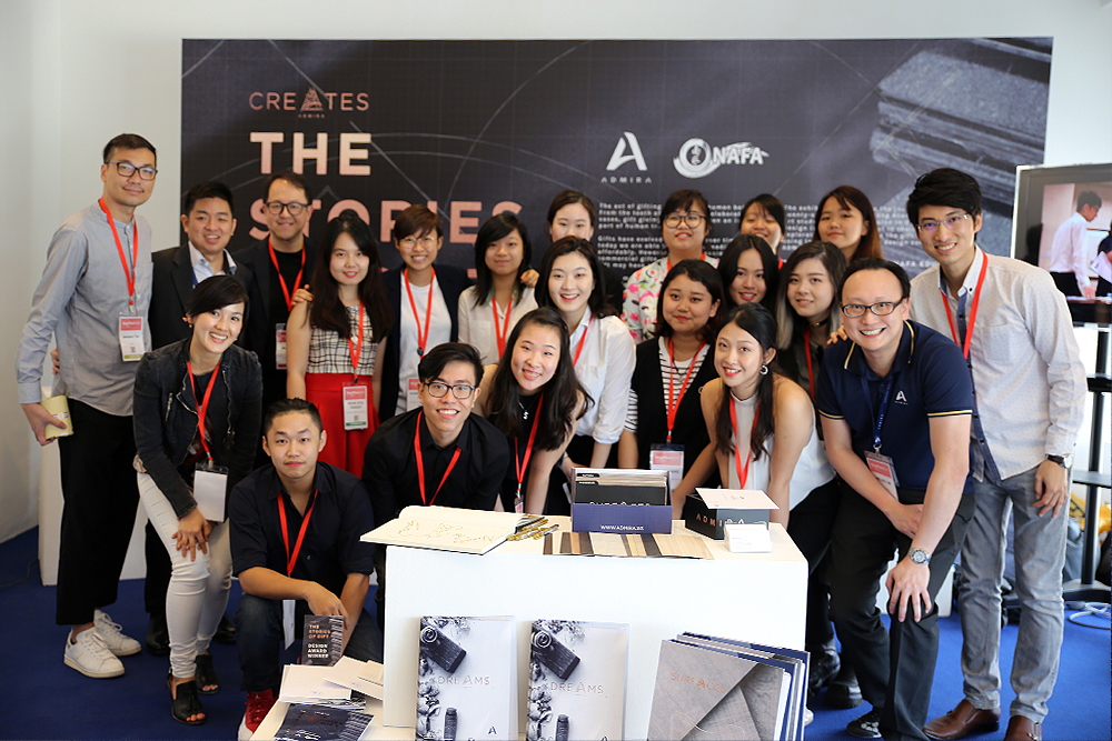 Group of about 20 people with red lanyards posing for a photo at a conference, in front of a dark event banner.